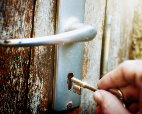 Hand unlocking battered old wooden door